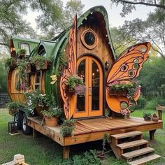 a house made out of wood and plants on the outside, with an orange butterfly wing