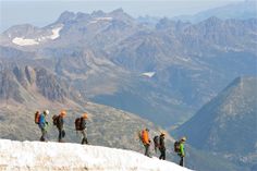 a group of people with backpacks standing on top of a snow covered mountain side