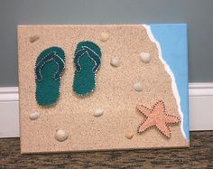 a pair of flip flops and starfish are on the sand with seashells