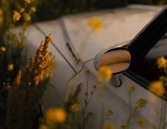 a car that is sitting in the grass with its door handle open and flowers around it