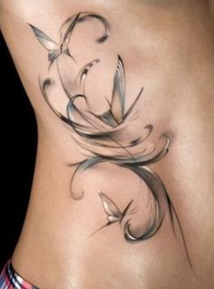 a woman's stomach with an artistic tattoo design on the side, and birds flying around