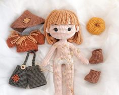 a crocheted doll and other items are laying on a white sheet with some yarn