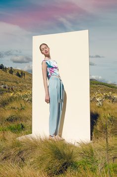 a woman standing in front of a large white box on top of a grass covered field