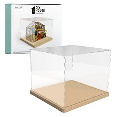 a clear plastic box with a house inside it and a cardboard base in the front