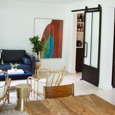 a living room filled with furniture and a painting on the wall above a wooden table