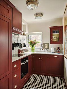 a kitchen with red cabinets and black and white checkered flooring on the tile