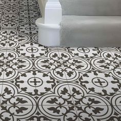 a bathroom floor with black and white tiles on the ground, in front of a bathtub