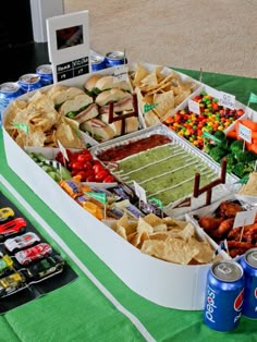 a large tray filled with lots of food and drinks on top of a green table cloth