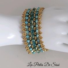 the bracelet is made with gold beads and blue glass beadwork on top of a white mannequin's head