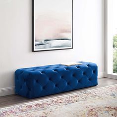 a blue bench sitting on top of a wooden floor next to a rug and window