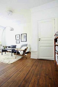 an image of a living room with white walls and wood flooring in the middle