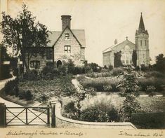 an old black and white photo of a house with a garden in the foreground