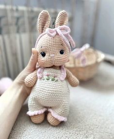 a small crocheted bunny doll sitting on top of a table next to a basket