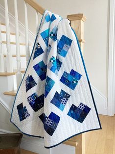 a blue and white quilt hanging from the side of a stair case next to a banister