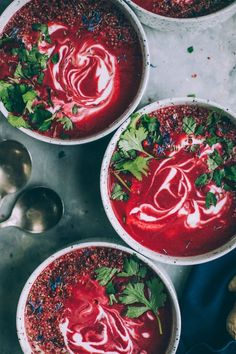 three bowls filled with red soup and garnished with cilantro