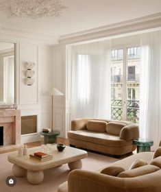 a living room filled with furniture and a fire place in front of a mirror on the wall