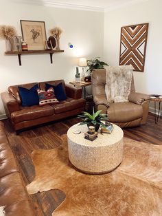 a living room with two brown leather couches and a round coffee table in the center