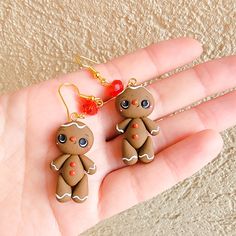 two small gingerbread cookies are being held in someone's hand with red beads