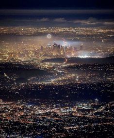 an aerial view of the city lights at night from above, with fog in the air