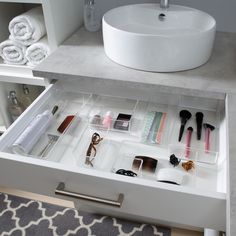 an organized drawer in a bathroom with toiletries and makeup products on the bottom shelf