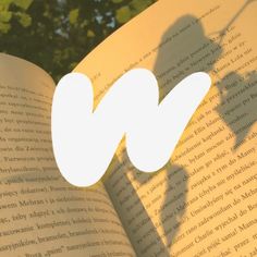 an open book with the shadow of a person's hand on top of it