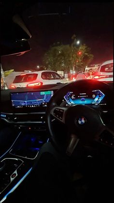 the interior of a car at night with several cars in the background and lights on