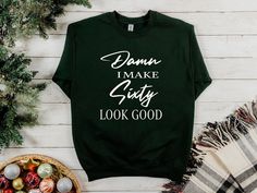 a green sweatshirt with the words damn i make city look good on it next to christmas decorations