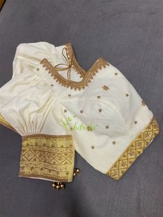 The blouse is made of premium quality ivory color Kerala Handloom Kasavu Vastra.. The blouse sleeve and neckline is beautifully embroidered with golden Jerry, zardosi, beads and kundan stones. The blouse hook opening at the back side and is lined with cotton fabric. The aari work boarder with puff sleeves gives it unique and elegant look. Note : The size chart mentions Body Measurements and note the garment dimensions. Fabric- Premium quality Kerala handloom kasavu. Color- Ivory with gold Kasavu Golden Beads Work On Blouse, Blouses Puff Sleeves, Elegant Off-white Traditional Wear With Unstitched Blouse, Cream Blouse With Puff Blouson Sleeves, Cream Blouse With Blouson Bishop Sleeves, Cream Blouse With Blouson Puff Sleeves, Elegant Off White Blouse With Pallu, Elegant Off-white Blouse With Pallu, White Blouse With Zari Work For Festivals