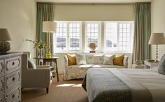 a bed room with a neatly made bed and two lamps on either side of the bed