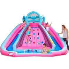 an inflatable water slide with two girls playing on it and another girl standing next to it