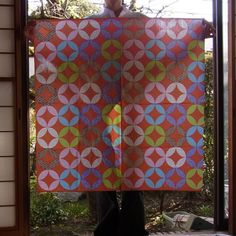 a man holding up a quilt in front of a window