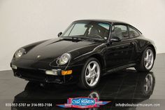 a black porsche parked on top of a tile floor next to a white wall in a room