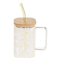 a glass coffee mug with a wooden lid and flower design on the outside, in front of a white background