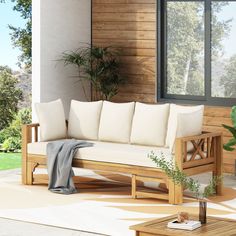 a white couch sitting on top of a wooden floor next to a window and potted plant