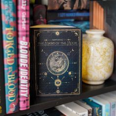 a bookshelf filled with lots of books next to a vase and other items