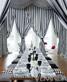 a dining room with black and white striped drapes on the windows, table set for four