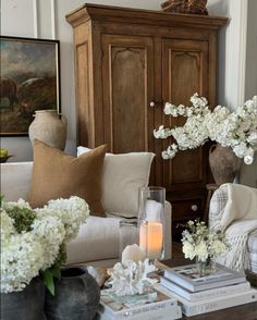 a living room filled with furniture and flowers on top of a coffee table in front of a cabinet