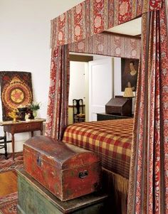 an old trunk is sitting on the floor in front of a bed with red and white bedspread