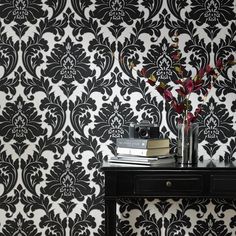 black and white damask wallpaper with flowers in vase on small table next to books