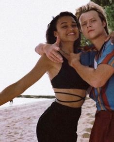 a man and woman standing next to each other on the beach