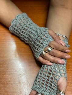 a woman's hand with two rings on it and a crochet glove