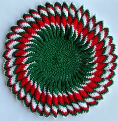 a crocheted red and green dishcloth on a white surface with stripes in the center