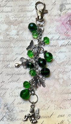 a key chain with green beads and charms on top of an old piece of paper