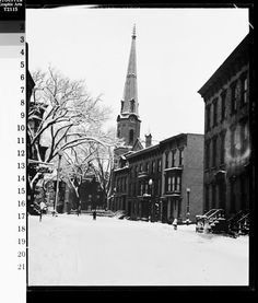 an old black and white photo of a church steeple in the background with snow on the ground