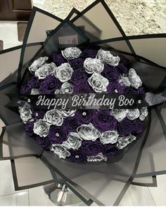 a birthday cake decorated with purple and white roses