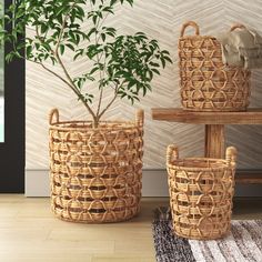 two woven baskets sitting on top of a wooden table next to a potted plant