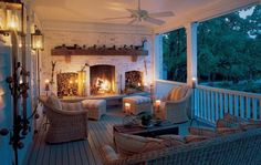 the porch is decorated with wicker furniture and lit candles on each side, along with an outdoor fireplace