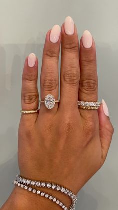 a woman's hand with three different rings on her fingers and two diamond bracelets