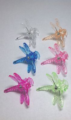 four different colored dragonflys are on a white surface with no one around them