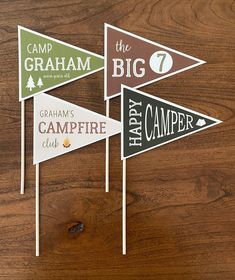 three camp flags on top of a wooden table